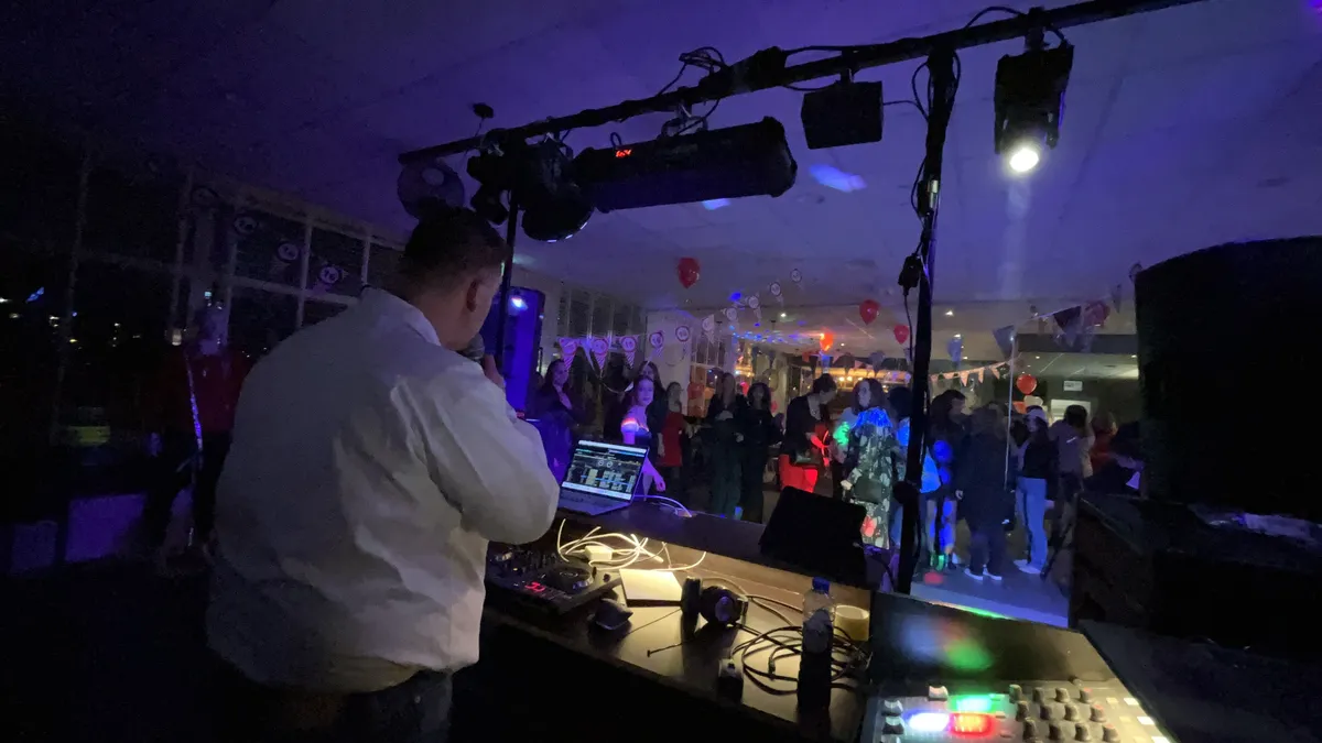 Feest DJ van O-Ke Entertainment achter zijn set met een volle dansvloer op de achtergrond